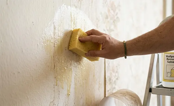 a hand holding a sponge cleaning the wall