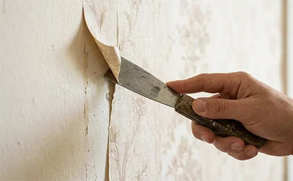 a hand scraping a wallpaper using a putty knife1