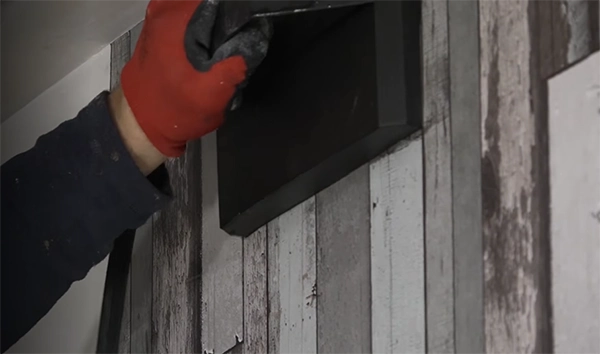 a person’s hand holding a water steamer on the wall